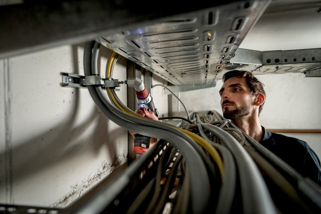 Mitarbeiter prüft, Kabelmanagement, elektrischer Schrank, akkuschrauber, Arbeiter im Einsatz