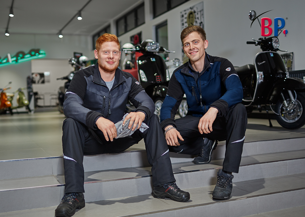 two men, motorradgeschäft, auf treppenstufen sitzt, arbeitskleidung, motorräder im hintergrund